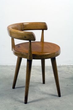 a wooden chair sitting on top of a cement floor in front of a white wall