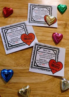 three valentine's day cards on a table with foil hearts around them and some candy in the background