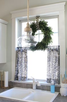 a kitchen sink with a wreath hanging from the window