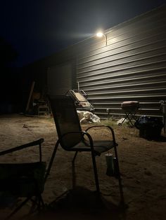 an empty lawn chair sitting in front of a building at night with the lights on