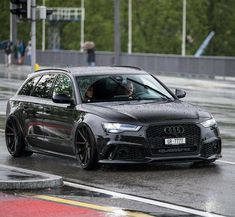 a black car driving down the street in the rain