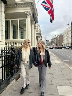 two women walking down the street with a union jack flag flying in the air above them