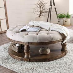 a round wooden coffee table sitting on top of a white rug in a living room