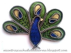 a green and blue peacock brooch with beading on it's back side