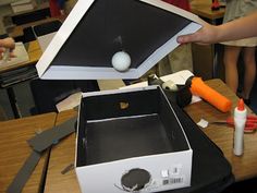 an open box sitting on top of a wooden table next to a person holding something in it