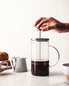 a person pours coffee into a glass mug