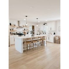 a large kitchen with white cabinets and wooden flooring, along with an island in the middle