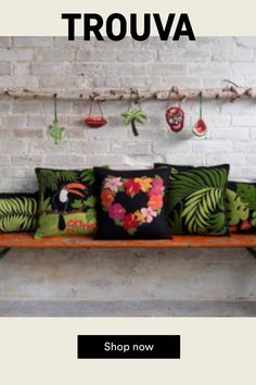 a wooden bench topped with lots of different colored pillows and decorations hanging from the ceiling