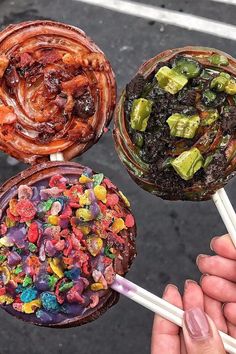 three lollipops with different toppings on them being held by two hands