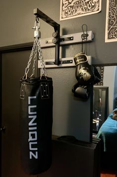 a black punching bag hanging from the wall next to a mirror in a room with pictures on the wall