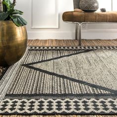 a black and white area rug in a living room with a gold vase on the floor