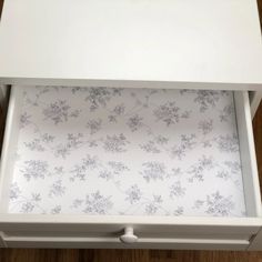 the drawer is open and has floral wallpaper on it's side paneling