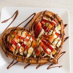 two heart shaped waffles with strawberries and chocolate drizzled on top