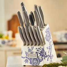 a set of knives sitting on top of a white box with blue flowers and vines