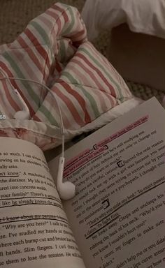 an open book sitting on top of a bed next to a pillow and headphones