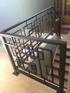 a metal stair railing with geometric designs on the bottom and sides, in an empty room