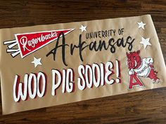 a sign that says university of arkansas, woo pig sool on the side of a wooden table