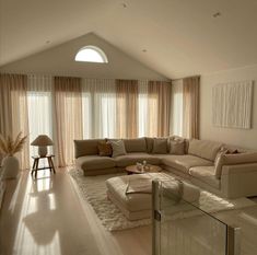 a living room filled with lots of furniture next to a tall white window covered in sheer curtains