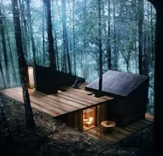 a small cabin in the woods with wood floors and walls, surrounded by tall trees