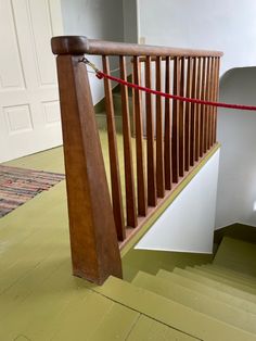 a wooden bannister with red rope on the top and bottom handrails