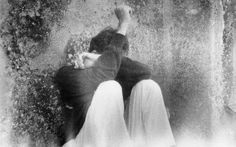 black and white photograph of two people leaning against a wall with their hands in the air