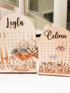 two wooden earring holders sitting on top of a white table next to a mirror