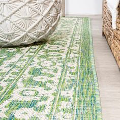 a green and white area rug on the floor next to two wicker bins