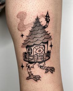 a tattoo on the leg of a person with a small house and stars around it