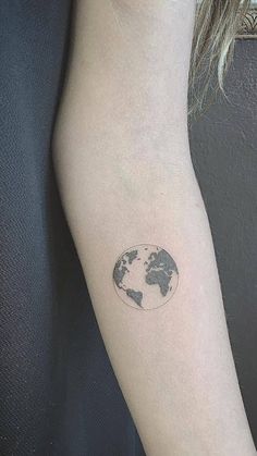 a small earth tattoo on the left arm is shown in black and grey colors,