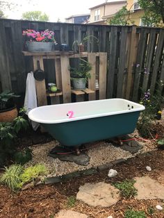 an old bathtub in the middle of a garden with potted plants on it