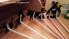 some paper cut out animals on top of a wooden table with straws in front of them