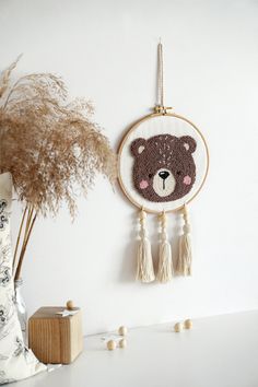 a teddy bear is hanging on the wall next to a plant and vase with dried grass