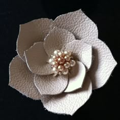 a white flower with some pearls on it's center and the petals are made out of leather