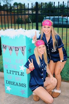 two young women posing in front of a sign