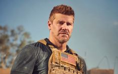 a man wearing a vest with an american flag patch on it and looking at the camera