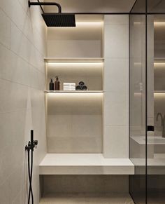 a modern bathroom with white walls and flooring is lit by recessed lighting, along with built - in shelving