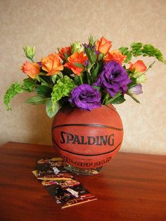 a basketball sitting on top of a wooden table next to some flowers and crackers