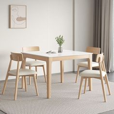 a dining table with four chairs and a vase on the floor in front of it