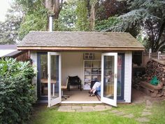 a man sitting in the doorway of a small shed