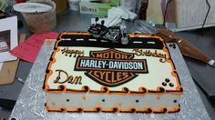 a harley davidson cake sitting on top of a silver plate covered in orange frosting