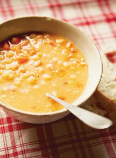 a bowl of soup and some bread on a table