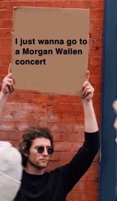 a man holding up a sign that says i just wanna to be a morgan wallen concert