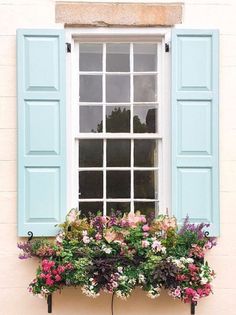 an open window with blue shutters and flowers in the planter on the outside