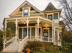 a green and white victorian style house with porches