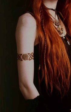 a woman with long red hair and tattoos on her arm