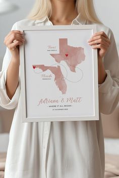 a woman holding up a framed map of the state of texas