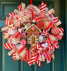 a christmas wreath on the front door with candy canes and a gingerbread house