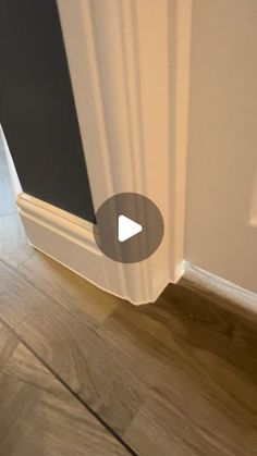 the corner of a room with a white door and wood flooring in front of it