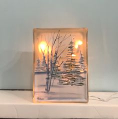 a glass block with some lights in it on top of a mantle next to a tree