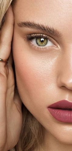 a close up of a woman's face with her hand on her head and one eye open